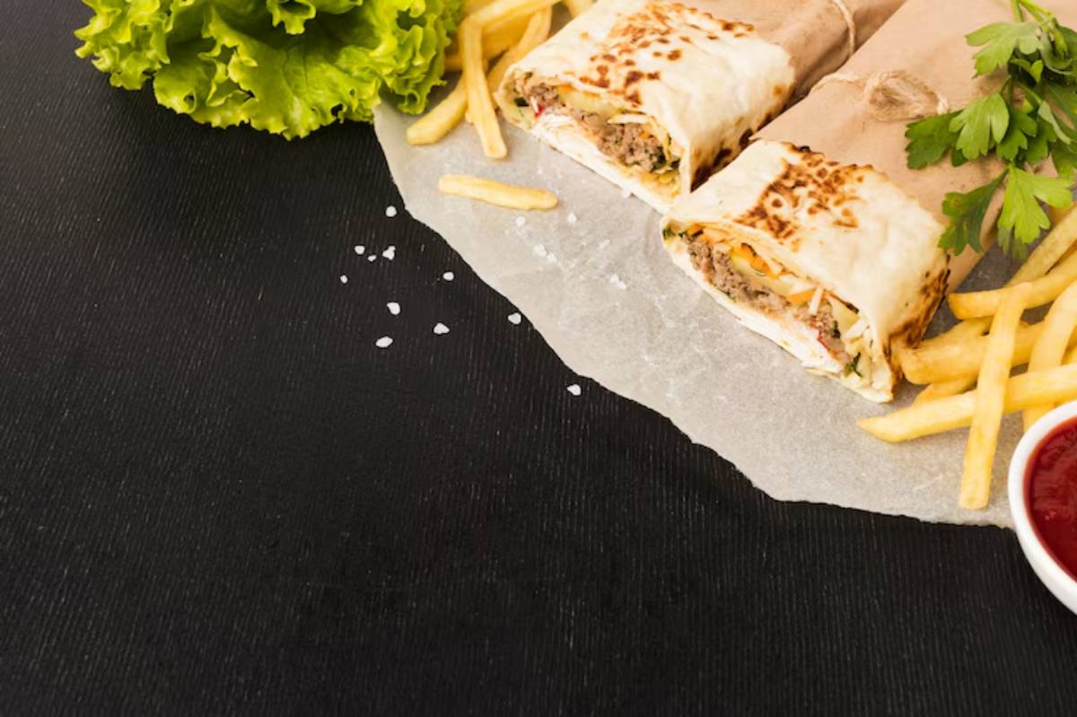 Two stuffed wraps with lettuce, meat, and veggies, served with fries and a side of ketchup on a dark wooden table.