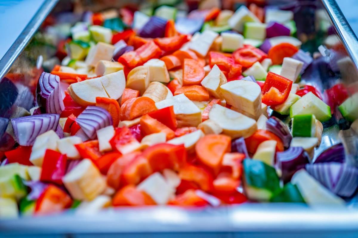 A vibrant assortment of chopped vegetables, including onions, bell peppers, carrots, and zucchini, neatly arranged in a tray.