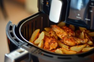 Air fryer filled with golden chicken wings and crispy potato wedges, ready to be served.